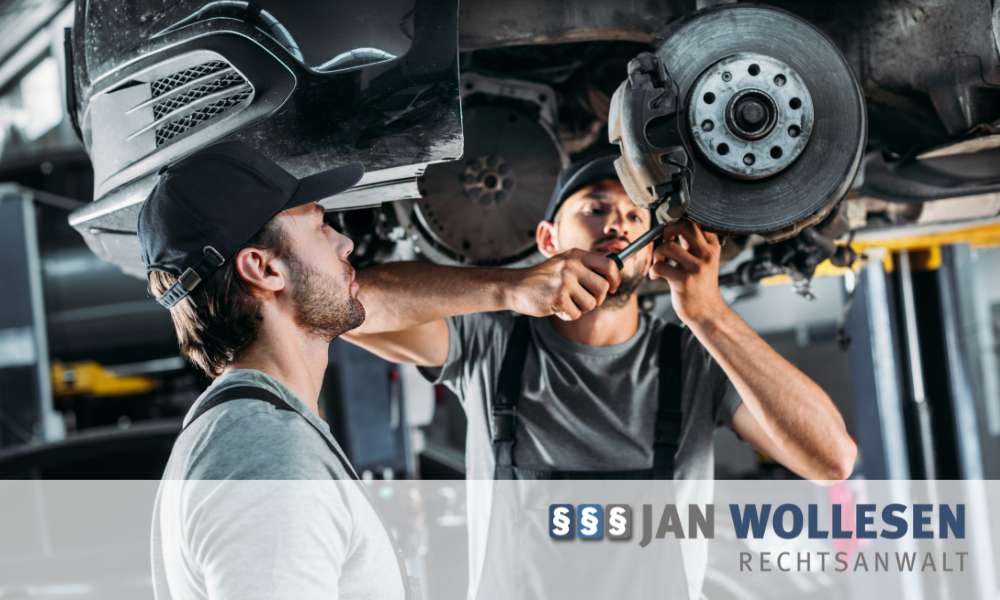 Zwei Kfz-Mechaniker reparieren ein Fahrzeug auf einer Hebebühne in einer Autowerkstatt.